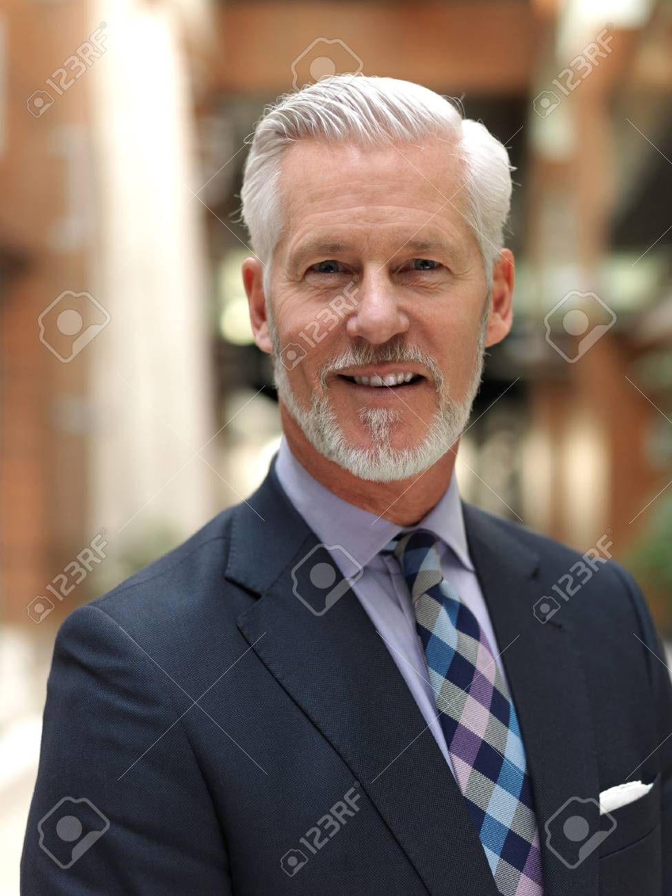 白髪交じりの正装で、髭を生やした年配のビジネスマンが屋外にいて、飲み物のカップを持っています。の写真 – Unsplashの事の画像