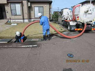 男が乾いた葉やがれきから排水管の側溝を掃除する側溝排水路の混雑と破損の防止Premium写真