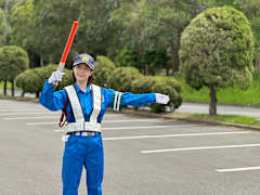 日本興志_総合建設_案内をする女性警備員の姿 - 心を繋いで未来を創る。日本興志